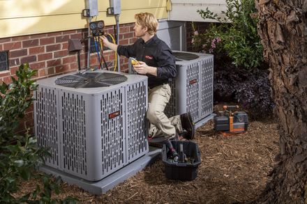 A technician taking readings at two outdoor condensing units.